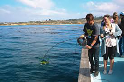 A group of children practicing fishing techniques during an education program in Newport Beach.